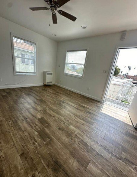 A room with a ceiling fan and wood flooring.